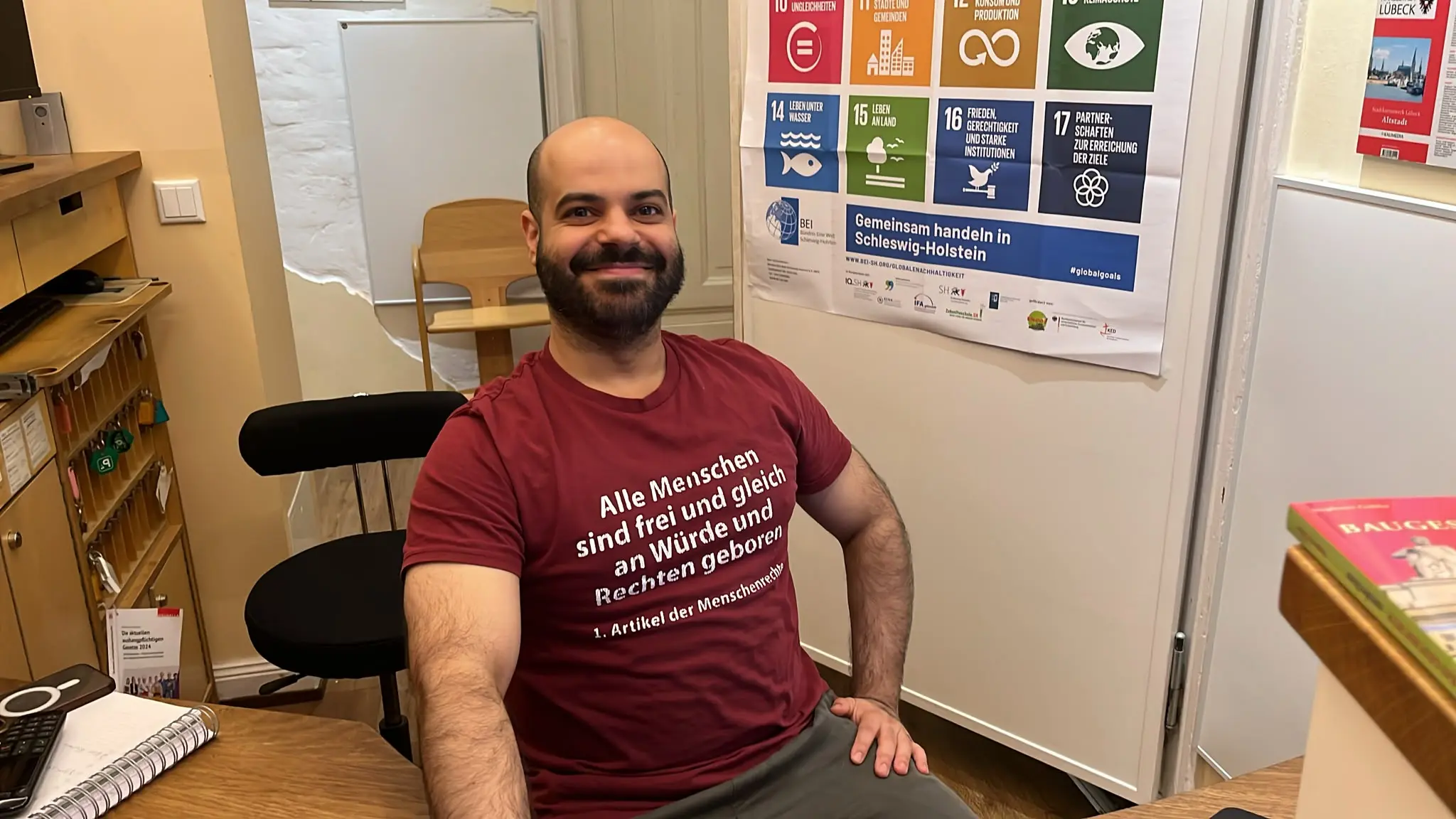 Mitarbeiter an der Rezeption im Hotel zur alten Stadtmauer in Lübeck trägt das T-Shirt mit Artikel 1 der Menschenrechte